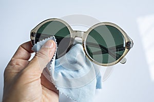 Woman left hand cleaning sunglasses by microfibre cleaning cloths, On white background, Close up & Macro shot, Optical concept