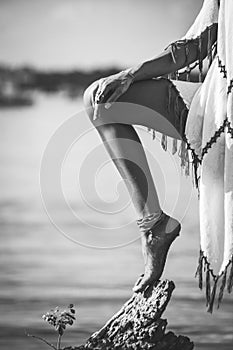 Woman leg and hand lean on tree on beach boho vibes look in white  tassel dress black and white