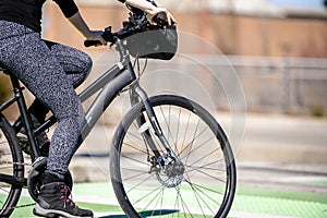 Woman in leggings and boots riding bicycle taking care of her health