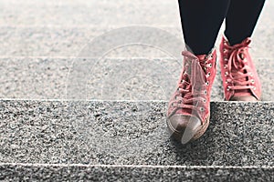 Woman legs in black leggings and pink sneakers climbing stairs outdoor