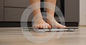 Woman legs checking weight. Female barefoot on scales measuring weight, close up. Weight loss concept