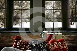 Woman legs in christmas socks on wooden table, christmas decoration, snowy winter outside the big window background.