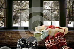 Woman legs in christmas socks on wooden table, christmas decoration, snowy winter outside the big window background.