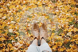 Woman legs in cowboy boots on the autumn leaves.