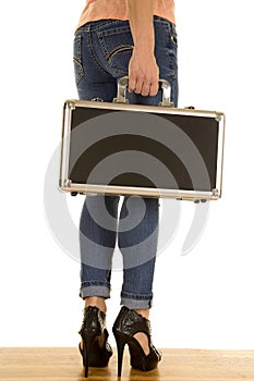 Woman legs in denim jeans hold case back