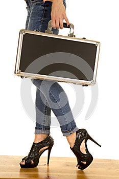 Woman legs in denim jeans hold case side