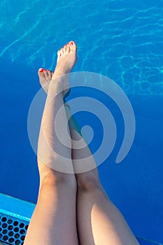 Woman legs while enjoying at the pool