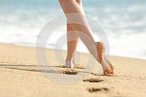 Woman legs and feet walking on the sand of the beach