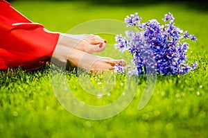 Woman legs on green grass with flower dress. Summer vacation concept. backlit