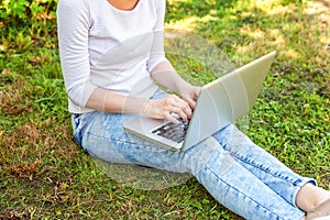 Woman legs on green grass lawn in city park working on laptop pc computer. Freelance business concept