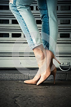 Woman legs in high heel shoes and blue jeans in city