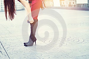 Woman legs in high heels black boots on street background, soft