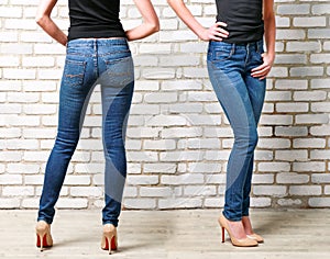 Woman legs in jeans on brick wall background