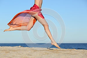Woman legs jumping on the beach happy