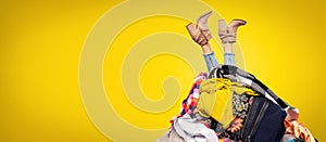 Woman legs out of clothes pile on yellow background