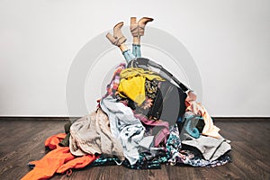 Woman legs out of a pile of clothes on the floor