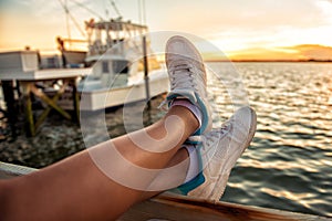 Woman legs over the sea bay and yachts at sunset time