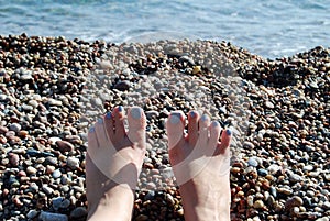 Woman legs on pebble beach