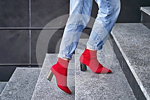 Woman legs in red sexy trendy stretch knitted fabric pointed toe block heel sock boots shoes and blue denim jeans pants