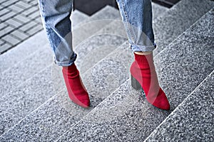 Woman legs in red sexy trendy stretch knitted fabric pointed toe block heel sock boots shoes and blue denim jeans pants