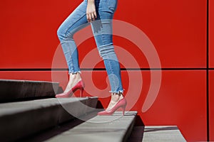 Woman legs with red shoes and red wall
