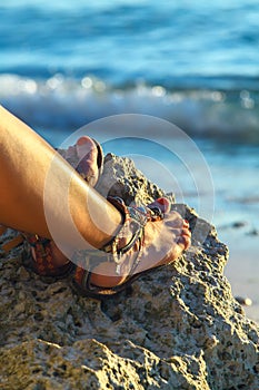 Woman legs with sandals on stone near tropical blue sea Philippines