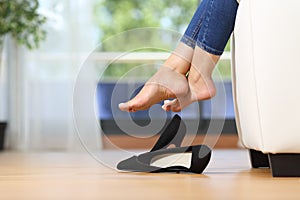 Woman legs and shoes resting on a couch at home