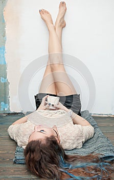 Woman with legs in shorts raised up on the wall holding cup of tea