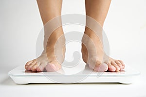 Woman legs stepping on floor scales, close-up