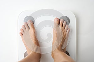 Woman legs stepping on floor scales, close-up