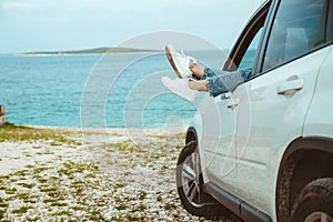 woman legs stick out from car parked at sea beach