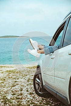 woman legs stick out from car parked at sea beach