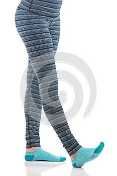 Woman legs while stretching exercise wearing colourful blue and grey striped sports pants and blue socks