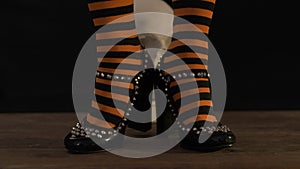 Woman legs in striped stockings and shoes knocking heels.