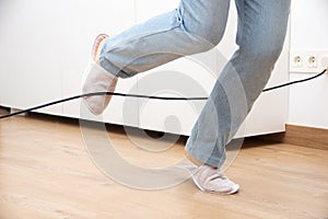 Woman legs stumbling with an electrical cord photo