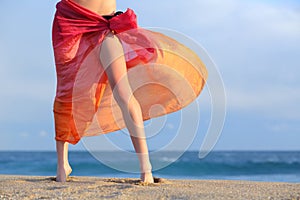 Woman legs on vacations posing on the beach with a pareo