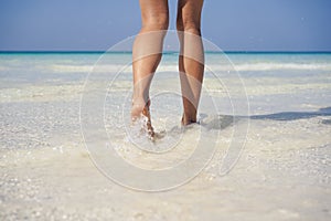 Woman legs walking on the beach sand