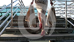 Woman legs walking on stairs with shopping bags