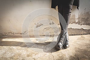 A woman legs wearing black boots with high heel.