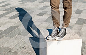 Woman legs wearing skinny brown trousers and black sneakers