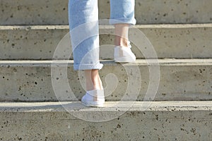 Woman legs wearing sneakers walking up stairs photo