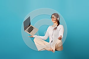 Woman levitates in lotus position with laptop.