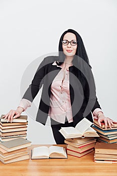 a female librarian teacher stands near a stack of books