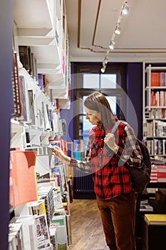 woman in a library or bookstore chooses a book to read. a European female student or a teaching researcher