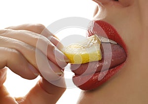 Woman licks and eating juicy lemon, close-up lips on a white background.