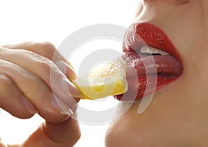 Woman licks and eating juicy lemon, close-up lips on a white background.