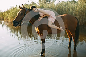 Woman lies astride a horse at river