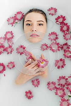 Woman lies in a bath with milk among the flowers