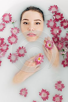 Woman lies in a bath with milk among the flowers