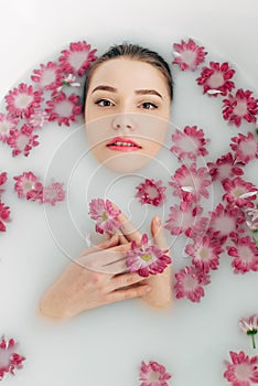 Woman lies in a bath with milk among the flowers